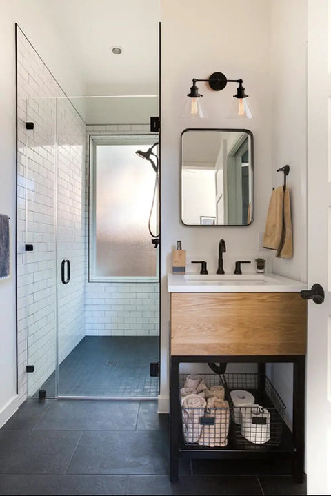Bathroom with Two Light Industrial Wall Sconce In Antique Black With 7.3 Inch Cone Clear Glass Shade above vanity.