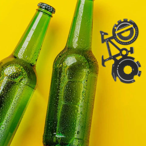 Compact Bicycle Shaped Multitool Keychain Made Of Stainless Steel next to two green bottles on yellow background