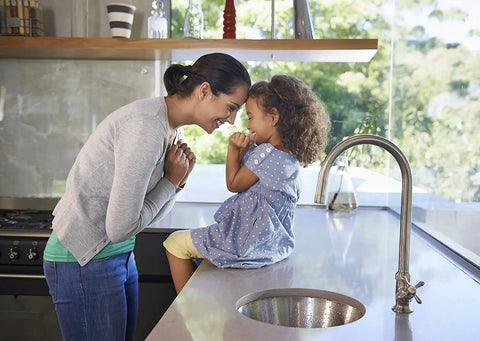 Mother and child smiling on a clean countertop protected by Premium Plus Stone Sealer Protector For Countertops Fights Stains On Natural Stone Marble And Granite With Built In Grime Guard Water Based Professional Grade Formula Easy Application Pint 16oz