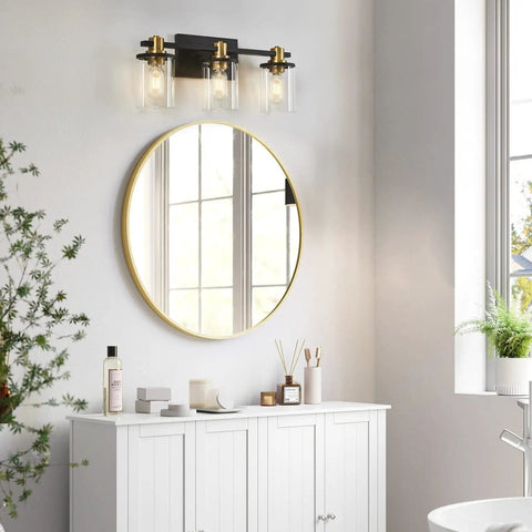 Three Light Black And Gold Bathroom Vanity Light Fixtures Over Mirror With Clear Glass Shade above round mirror
