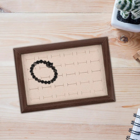 Solid Wood Earring Organizer And Ring Keeper Tray With Thirty Open Slots For Stashing Bracelets And Chains In A Rich Walnut Finish with a black bracelet.
