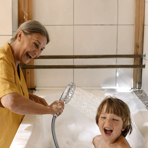 Woman using 8 Spray 2 In 1 Dual Shower Head With Handheld And Magnetic Dock Hose Included Detachable Pause Switch For Water Saving Chrome Finish Easy Snap On Off High Pressure Shower Combo to wash child's hair.