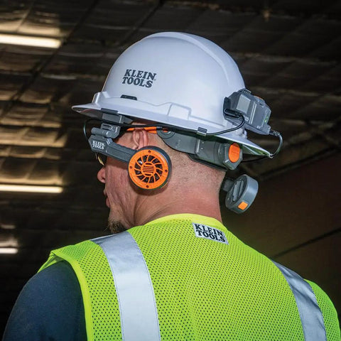 Worker wearing a white hard hat with Klein Tools branding and dual cooling fan for hard hats and safety helmets, USB-C rechargeable, on a job site.