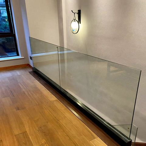 Heavy Duty Glass Railing System For Deck And Balcony Featuring Rock Solid Spigot Clamps With Flexible Floor Or Side Mount Hardware And Premium Aluminum Posts In Matte Black Covers For Quick Pool And Yard Fence Projects showcased indoors with wooden floor.