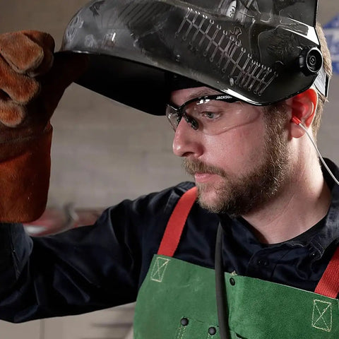 Man wearing Pro Grade Graphic Auto Darkening Welding Helmet With Digital ADF, ANSI Z87.1 Certified, lifting the visor mid-weld.