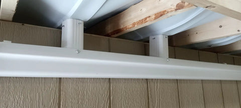 Dry Under Deck Drainage System Roll For 50 Feet installed, showing white downspout and black trough, fits 12 inch joists.