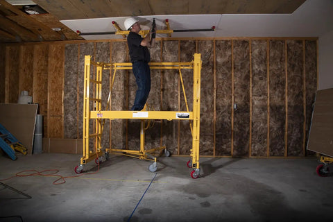 Worker using Heavy Duty Adjustable Work Platform Featuring Locked Safety Rails for ceiling repairs at 11 feet high.