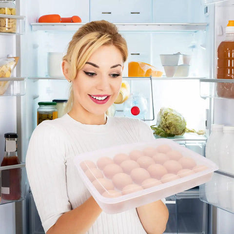 Person holding Two Pack Covered Egg Holder Set Clear Stackable Egg Trays in refrigerator, each tray holds 24 eggs, plastic storage.