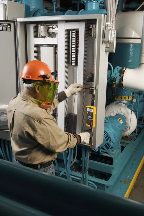 Technician using Beefed Up Pro Grade Industrial Digital Multimeter for troubleshooting in electrical panel with safety gear