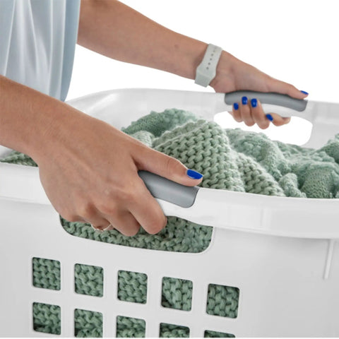 Person carrying Ultra 2 Bushel Plastic Laundry Hamper Baskets, 6 Pack in White with comfort grip handles filled with clothes