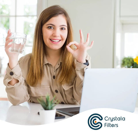 Woman smiling at a desk with a glass of water, representing fresh water using Compatible PUR Water Filter Replacement Cartridges 6 Pack