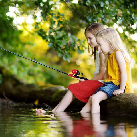 Two Pack Kid Friendly Fishing Pole Kit With Portable Telescopic Rod being used by two young girls at a pond