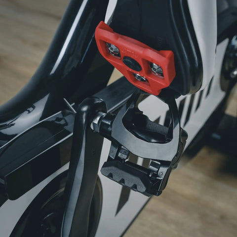 Red Look Delta Compatible Bike Cleats attached to indoor cycling pedal, showing 9 degree float, durable design, for Peloton and stationary bikes.
