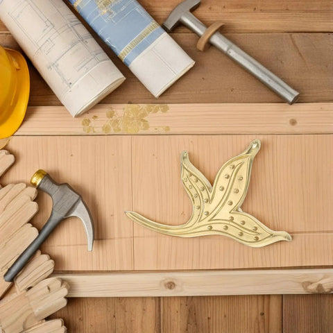 Brass Leaf Drawer Pulls For Cabinets And Wardrobes placed on wooden surface with design tools around, showcasing vintage kitchen cupboard hardware.