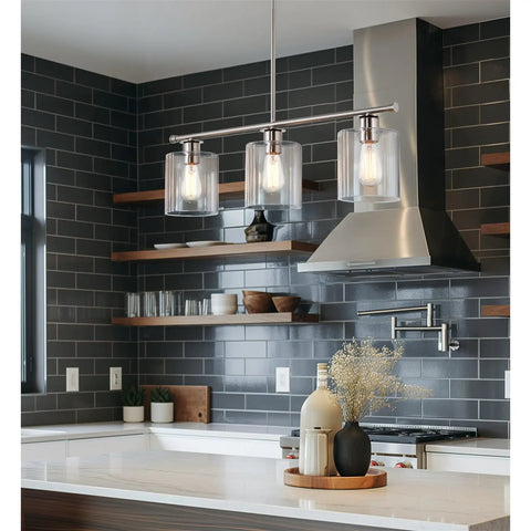 Three Light Kitchen Island Fixture With Clear Glass Cylinder Shades In Warm Brass Finish, shown above modern kitchen island.
