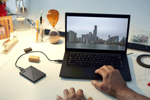 Person using laptop with 2TB Portable External Hard Drive With Ransomware Defense And Password Protection, USB 3.1 And USB 3.0 Compatible