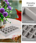 Three Piece Multi Grid Jewelry Organizer Trays Featuring Earring Stands Necklace Display Plates And Soft Velvet Ring Inserts To Make Sorting Your Bling A Breeze For Home Or Showroom Use on a table with floral decoration.