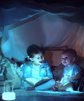 Kids reading under a blanket with a 35 Pack 3D LED Light Bases With Remote Control 16 Colors USB Powered Acrylic Night Lamps Stand nearby.