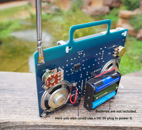 AM FM Radio Kit For DIY Soldering Projects And Electronics Teaching Hands On STEM Gift Dope Stereo Receiver Complete Parts Kit With Full Color Manual Upgraded VT-16 Version Easy Build For Beginners showing back circuit board and speaker assembly outdoors.