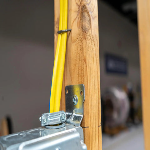 Yellow electrical wire installed in wooden frame with metal junction box for dry indoor use