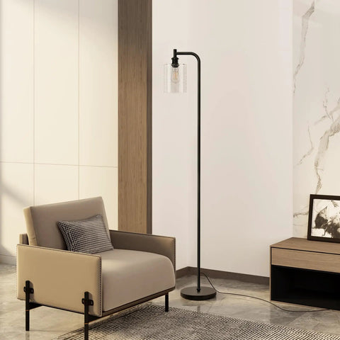 Modern Black Floor Lamp With Seeded Glass Shade Dope Bright LED Bulbs Industrial Tall Pole Standing Lamp For Living Room Bedroom Or Office Sleek Yet Sturdy Lighting That Fits Any Decor, placed beside a beige armchair in a modern living room.