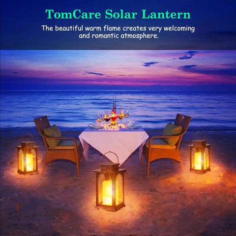 Lit Outdoor Solar Lantern With Realistic Flickering Flame, Metal Hanging Lanterns on a beach with a dining setup at sunset.