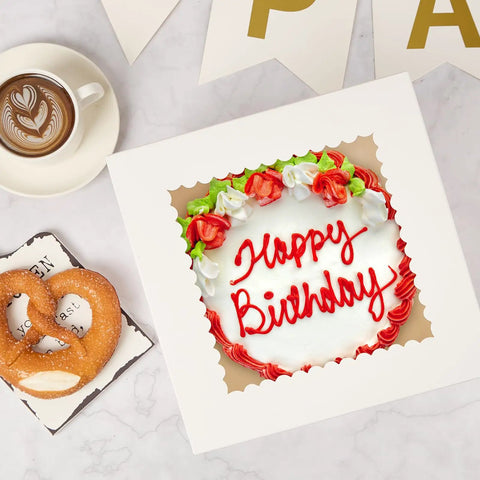 Top Tier 8 X 8 X 8 Inch Cake Boxes 4 Pack Featuring Clear Window with a birthday cake inside and a pretzel beside it.