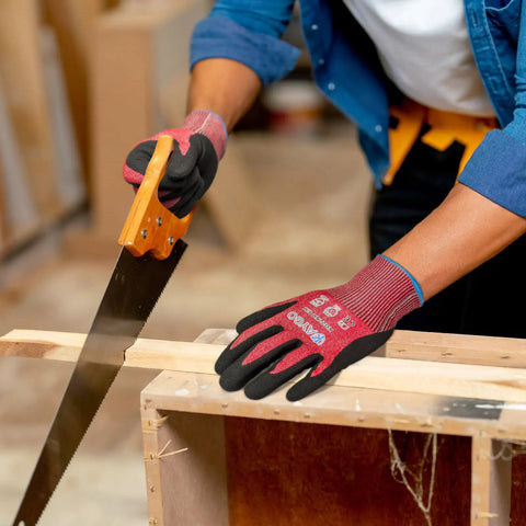 Person wearing Cut Resistant Nitrile Coated Safety Gloves With Firm Grip ANSI Cut A4 KG22N, sawing wood in a workshop.