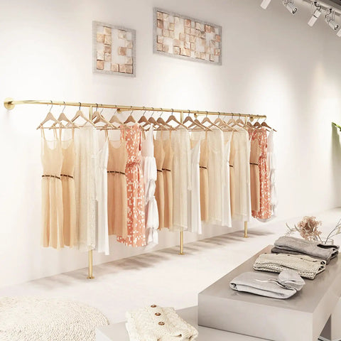 Top Tier Wall Mounted Garment Rack With Built In Shelves And Brushed Gold Finish Straight Ready For Any Boutique Or Master Closet Heavy Duty Metal Clothes Rail That Actually Holds Your Threads displaying dresses in a boutique.