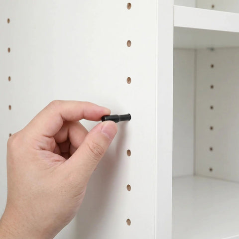 Hand inserting 24 Pack Shelf Pins For Cabinets And Wardrobes, 1/4 Inch Carbon Steel Dowel Pins With Rubber Covers into a cabinet hole.