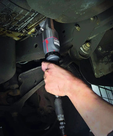 Pro Grade 1/2 Inch Air Impact Wrench in use under vehicle, showcasing right angle design and composite body for tough jobs.