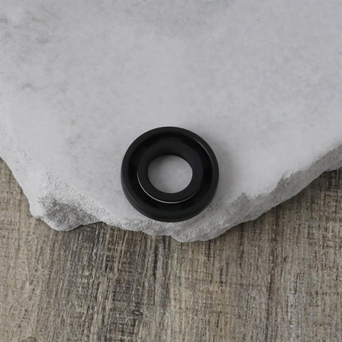 Close-up of black nitrile rubber oil seal with double lip, 12x24x4.5 mm, on stone surface