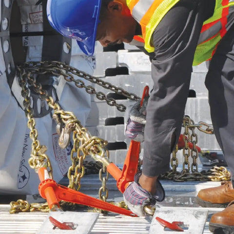 Worker using Beefy Ratchet Style Load Binder With Two Grab Hooks 7100 Lb Safe Working Load Fits 5/16 Or 3/8 Inch Grade 70 And Grade 80 Chain Forged Steel Pawl And Gear For Safe, Easy Tie Down on trailer