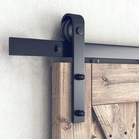 Heavy Duty Matte Black Barn Door Track Kit With No Sweat Hardware For Quick Single Door Install And Slick Modern Home Decor Upgrades Adjustable Top Rail System Fits Any Standard Opening Securely close-up on top rail and wheel with wooden barn door.