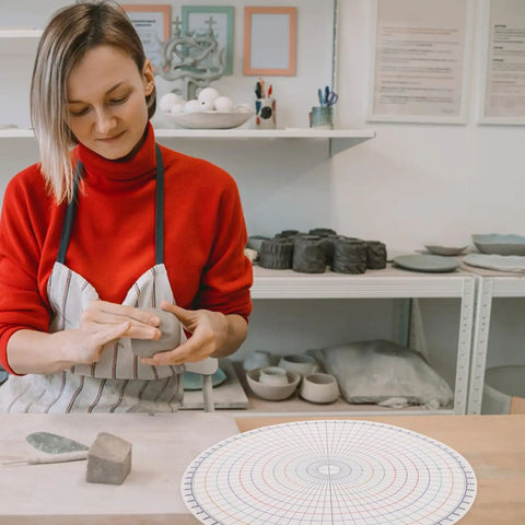Heavy Duty Pottery Circle Divider Lays Dead Center For Precision Clay Slab Layout And Ceramic Wheel Projects illustrating usage by an artist.