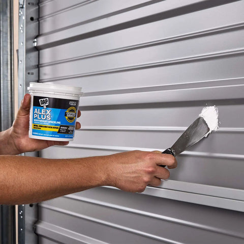 Hands applying Alex Plus Spackling White 32 Oz Quick Dry Patch For Drywall Wood And Metal No Sag No Shrink Pro Grade Strength on metal surface