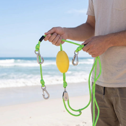 Close-up of automatically adjustable bungee dock line with center stainless steel pulley at beach, yellow and green color.