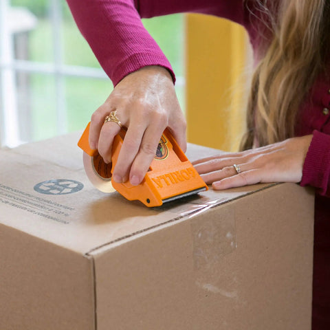 Person using Tough As Nails Clear Packing Tape For Moving And Storage 2.83 Inch By 30 Yard Two Rolls on a cardboard box.