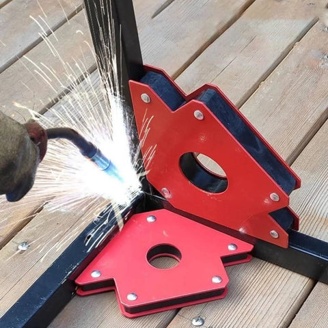 Welding metal with Six Piece Welding Magnet Set With Fixed Angles and Right Angle Positioners on wooden surface.