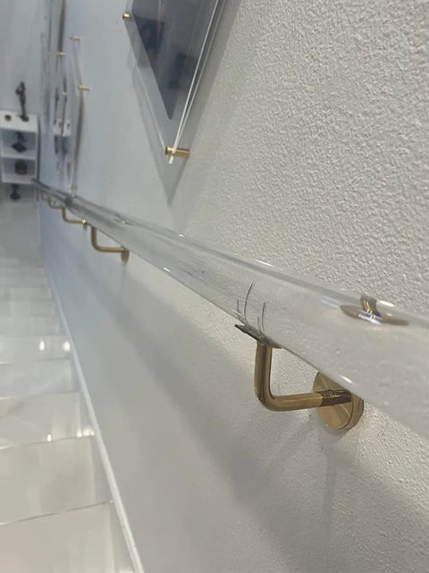 Clear Acrylic Stair Handrail With Gold Wall Brackets And Firm Grip Built Tough For Custom Indoor Banisters Rock Solid Heavy Duty Wall Mount Support Adjustable Lengths For Home Reno, installed along a wall.