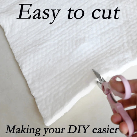 Ceramic fiber insulation blanket close-up being cut with pink-handled scissors; white, 39.4 x 24 x 0.5 in.
