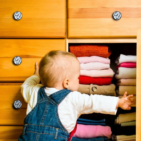 Child reaching for drawers featuring Dang Sharp Black And White Marble Look Round Cabinet Knobs 4 Pack with glossy crystal glass finish.