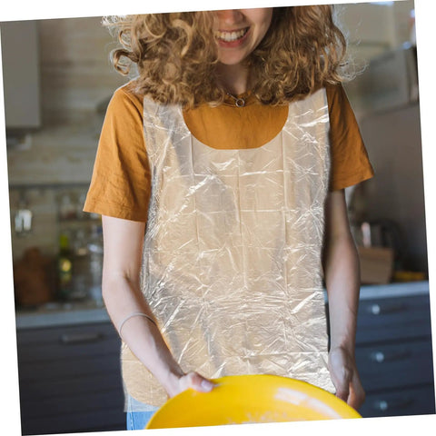 Get Ready To Tackle The Mess With This Slick Rock Solid Pack Of Twenty Five Chemical Resistant Waterproof Sleeveless Aprons In Transparent Plastic Perfect For Kitchen Grilling And Dirty Chores Giving You Zero Stress And Total Victory Today. Woman wearing a clear waterproof sleeveless apron, holding a yellow bowl.