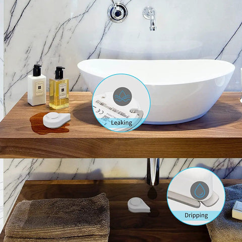 Zigbee Water Leak Sensor 4 Pack With Dripping Detection, 120 DB Alarm next to a bathroom sink, detecting water leak on wood surface.