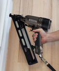 User operating Pro Grade 15 Gauge Finish Nailer Pneumatic With 34 Degree Angled Drive on wooden flooring