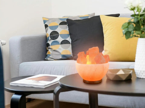 Himalayan Salt Lamp Bowl With Crystal Chunks, Dimmer Cord, And Classic Wood Base on coffee table in cozy living room