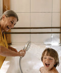 Smiling woman using Magnetic 2 In 1 Shower Head With Handheld Sprayer And On Off Water Saving Switch Eight Spray Hand Held Wand Flexible Anti Kink Hose Brushed Nickel Finish For Easy Docking And Strong Water Pressure to bathe a child in a tub.