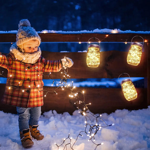Child in winter attire enjoying snowy evening with glowing LED jars, not a warm white LED glow candle with 12 hour illumination.