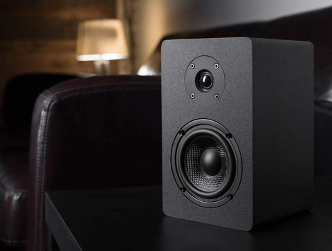 PB42X Powered Bookshelf Speakers With 30 Watt RMS, Near Field Studio Monitors in black, shown on a table in a home setting.