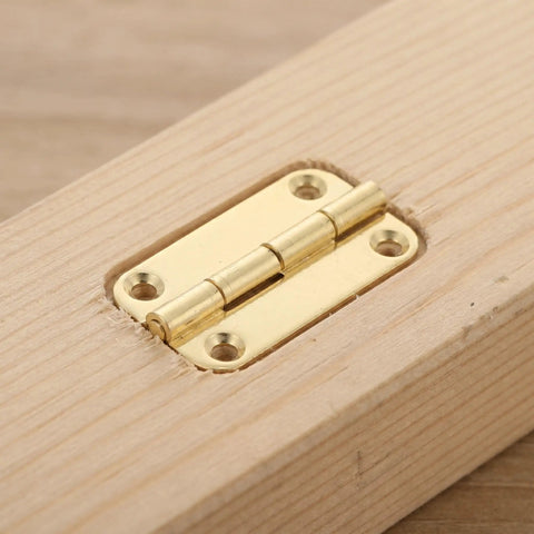 Close-up of Antique Mini Cabinet Hinges 1.5 Inch 12 Pack in Gold Tone on wood with rounded corners and four-hole vertical pattern.